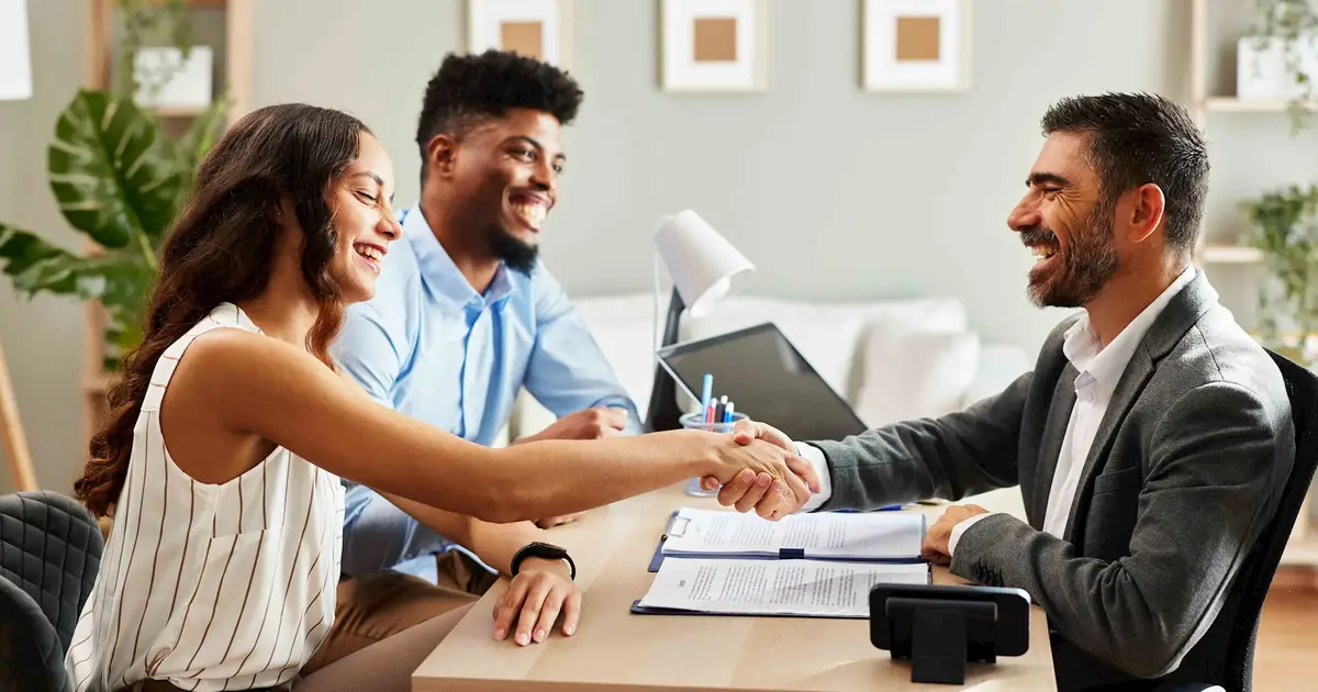 Couple shaking hands with professional, closing a deal.