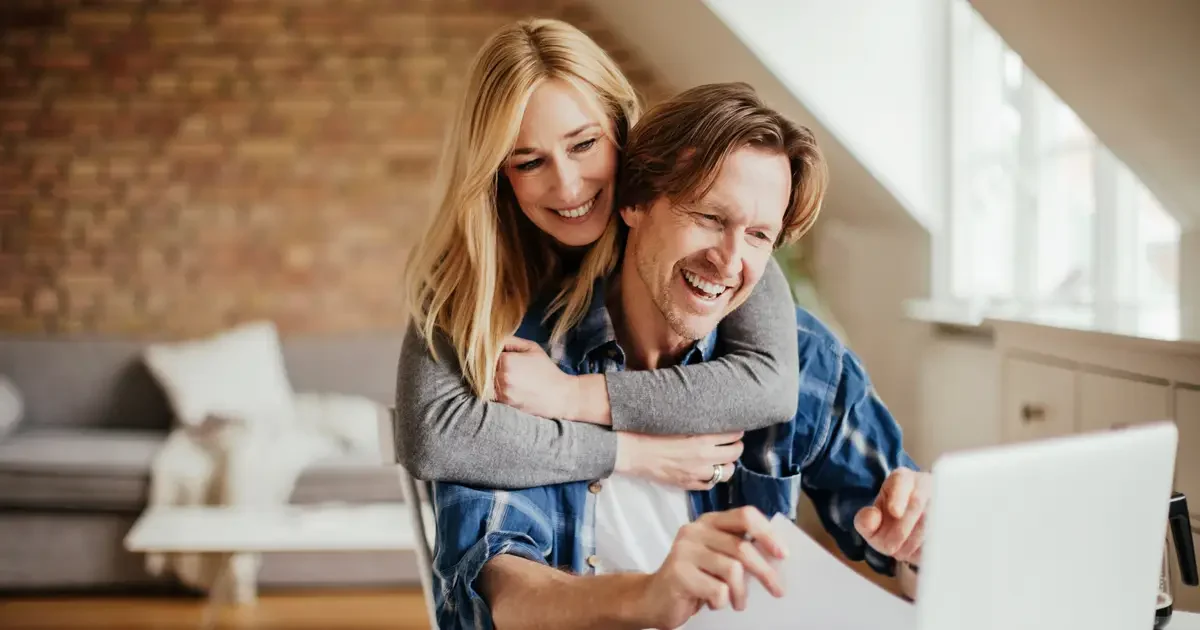 Man and woman embrace while looking at computer