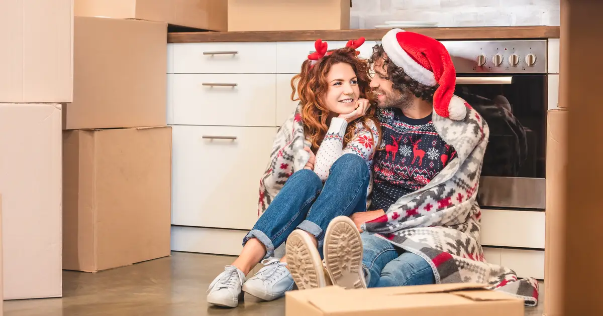 Couple in Santa hat sitting in new home with boxes