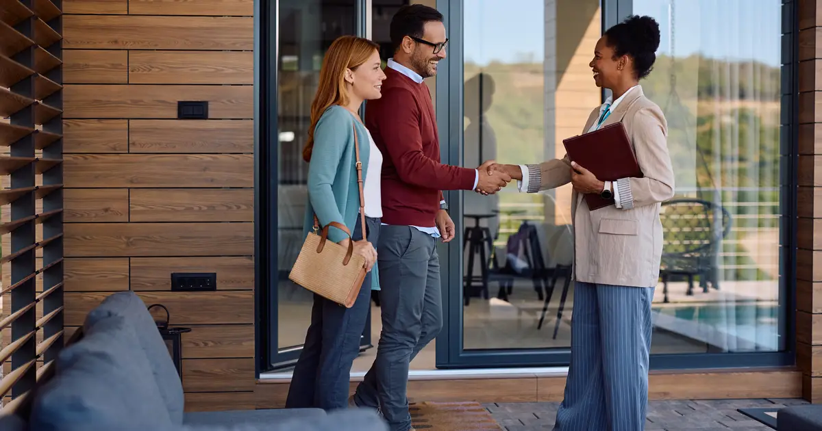 Happy couple shaking hands with agent